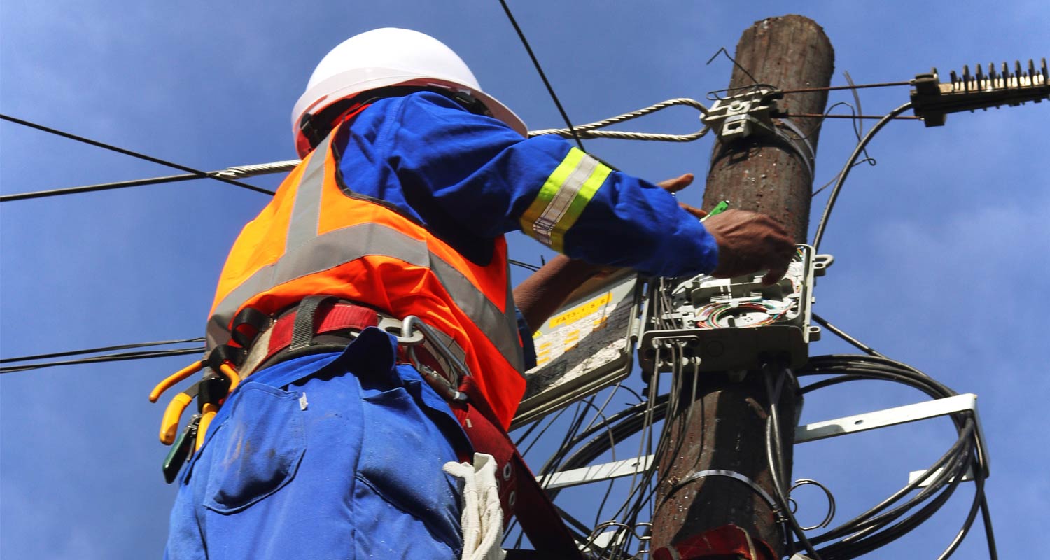 A technician for Ilitha Telecoms installing fibre on a pole
